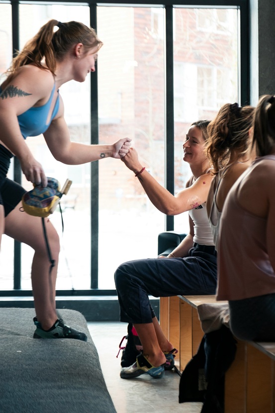 Two fitness women high-fiving to celebrate reaching a goal together